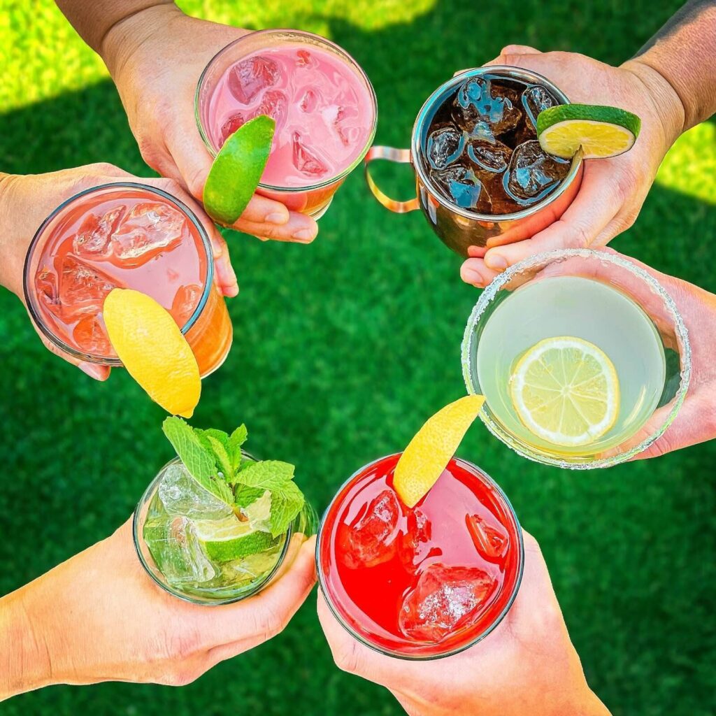 Different hands holding the six specialty spring cocktails.