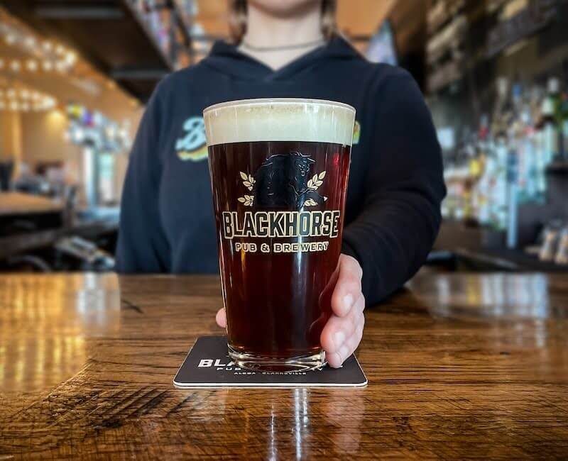 A Blackhorse branded glass with Brown Ale in it.